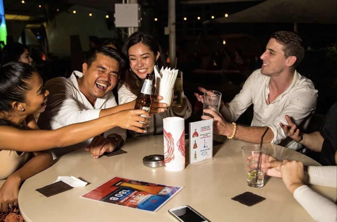 Guests laughing and toasting together at a Bangkok social night